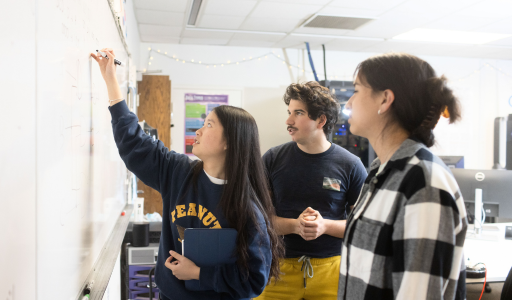 Students in a classroom writing on a white board